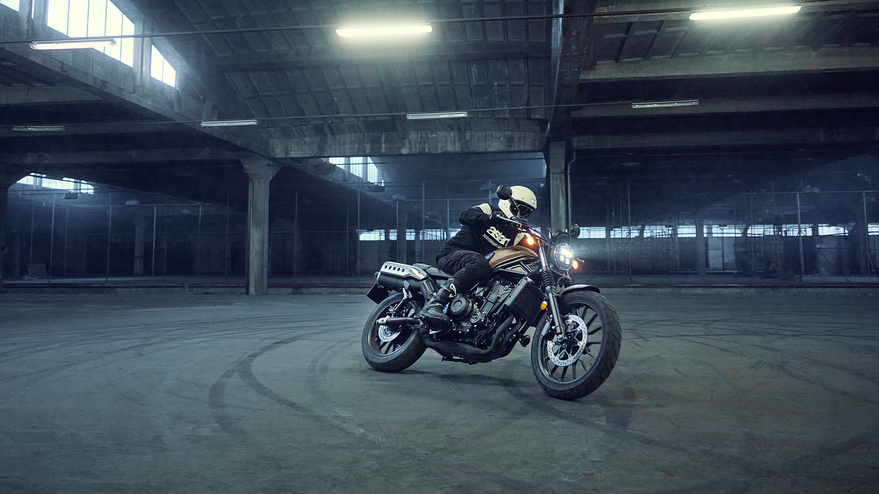 Modello/a alla guida di una moto Honda CL500 in un parcheggio.