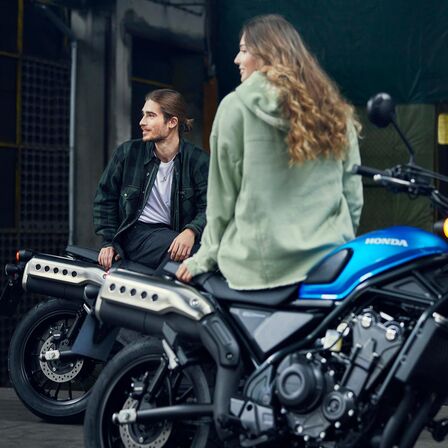 Honda CL500 con modelli seduti sulla moto.