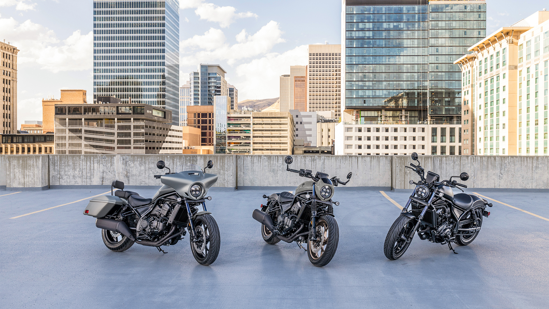 Tre moto CMX1100 all'esterno, davanti a edifici moderni.