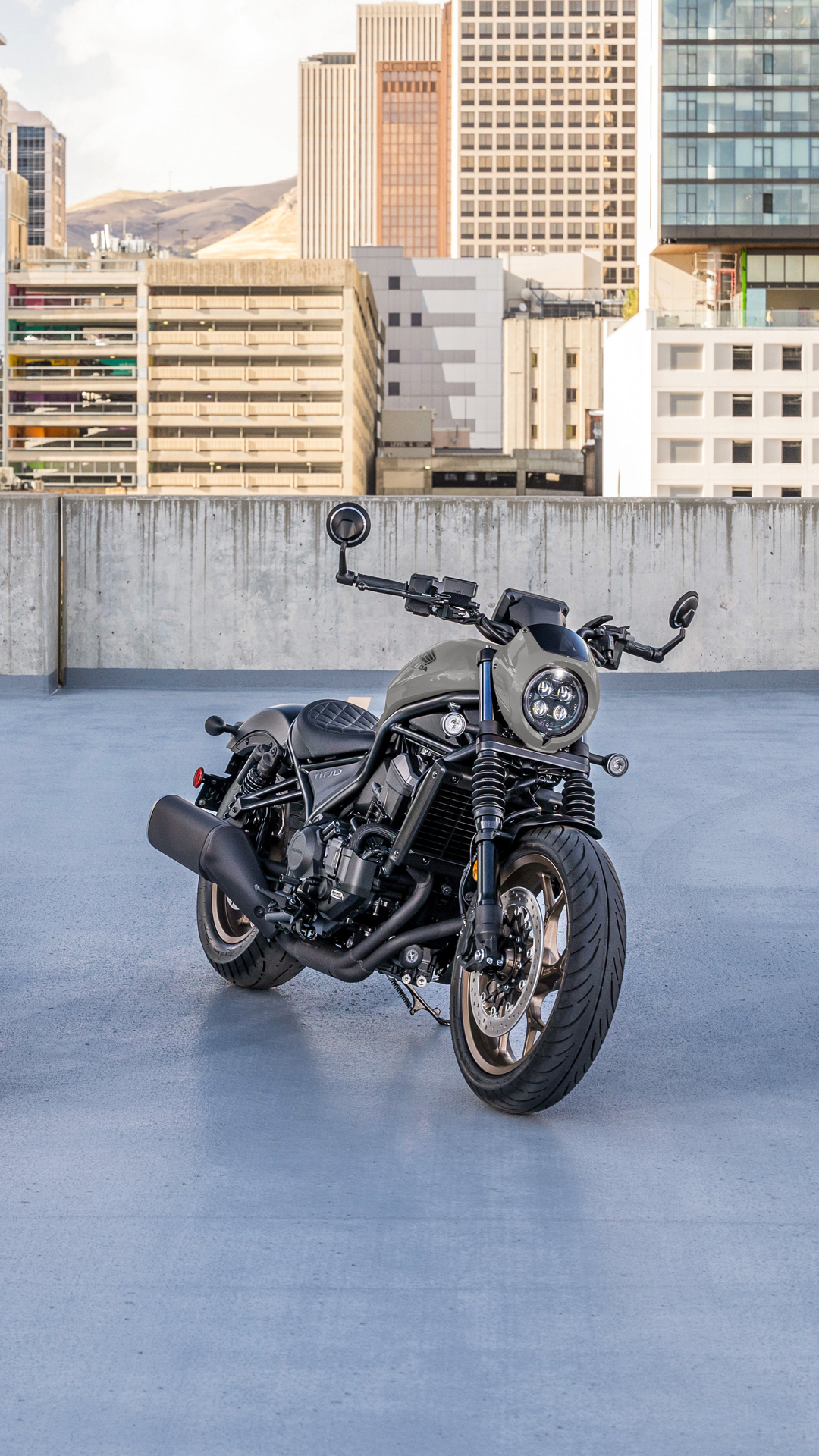 Una moto CMX1100 all'esterno, davanti a un edificio moderno.