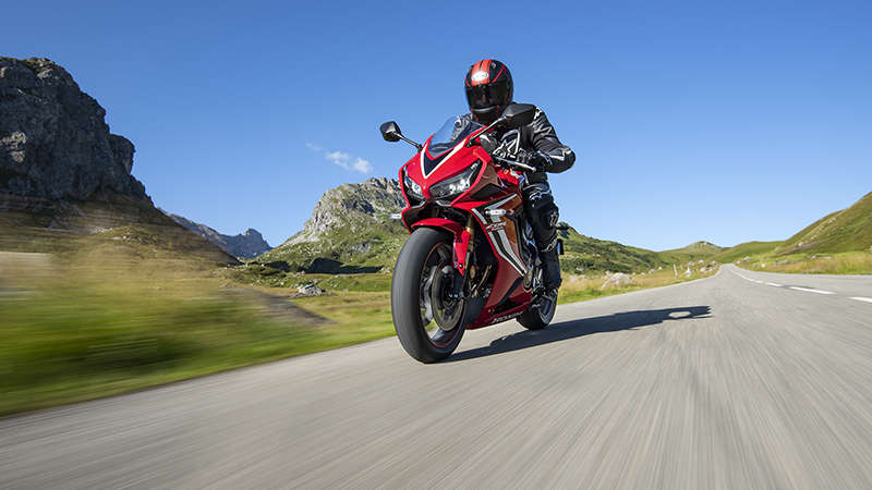 CBR650R, vista di tre quarti frontale sinistra, in azione con guidatore su una strada di montagna